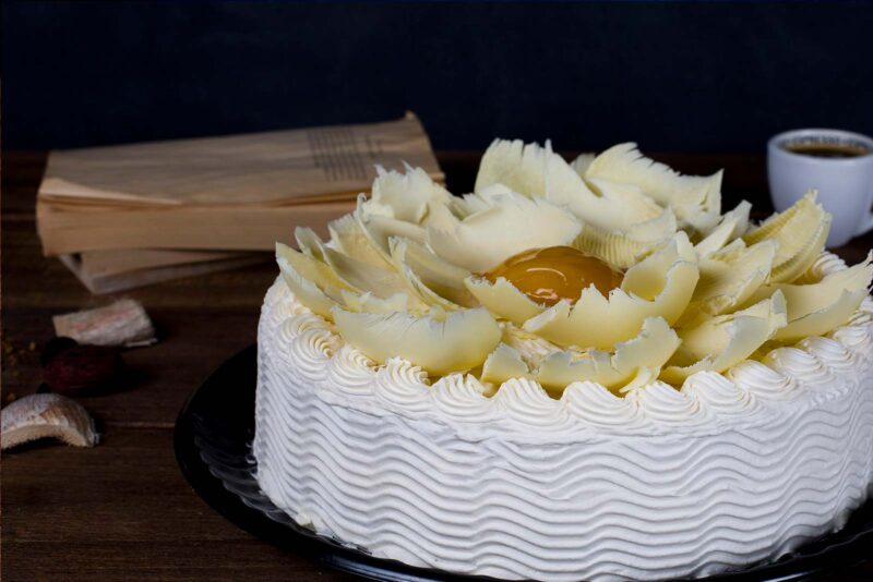 Pastel conquista de durazno de Lecaroz, decorado con hojuelas de chocolate blanco y durazno