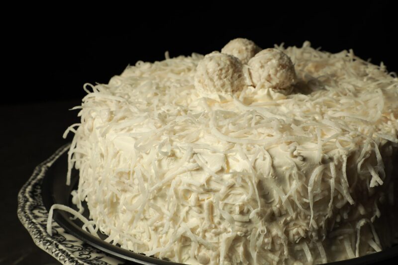 Pastel de coco de Lecaroz, decorado con trufa de coco, coco rallado y crema