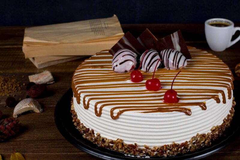 Pastel encanto de Lecaroz, decorado con crema blanca, cajeta, chocolate, fresas y cerezas